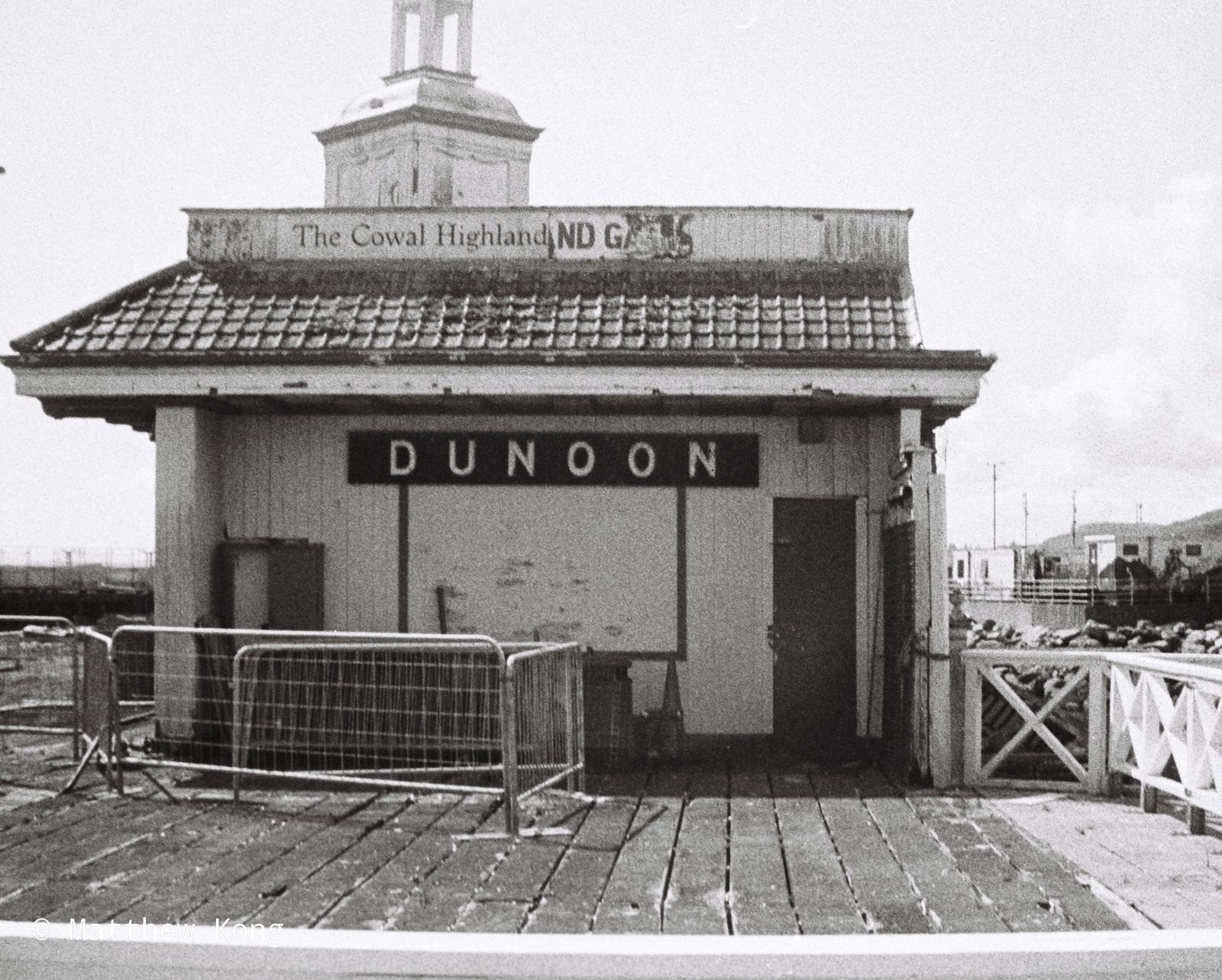 A boarded-up shack on the pier, DUNOON in white letters across its front and barriers pulled across the doorway.