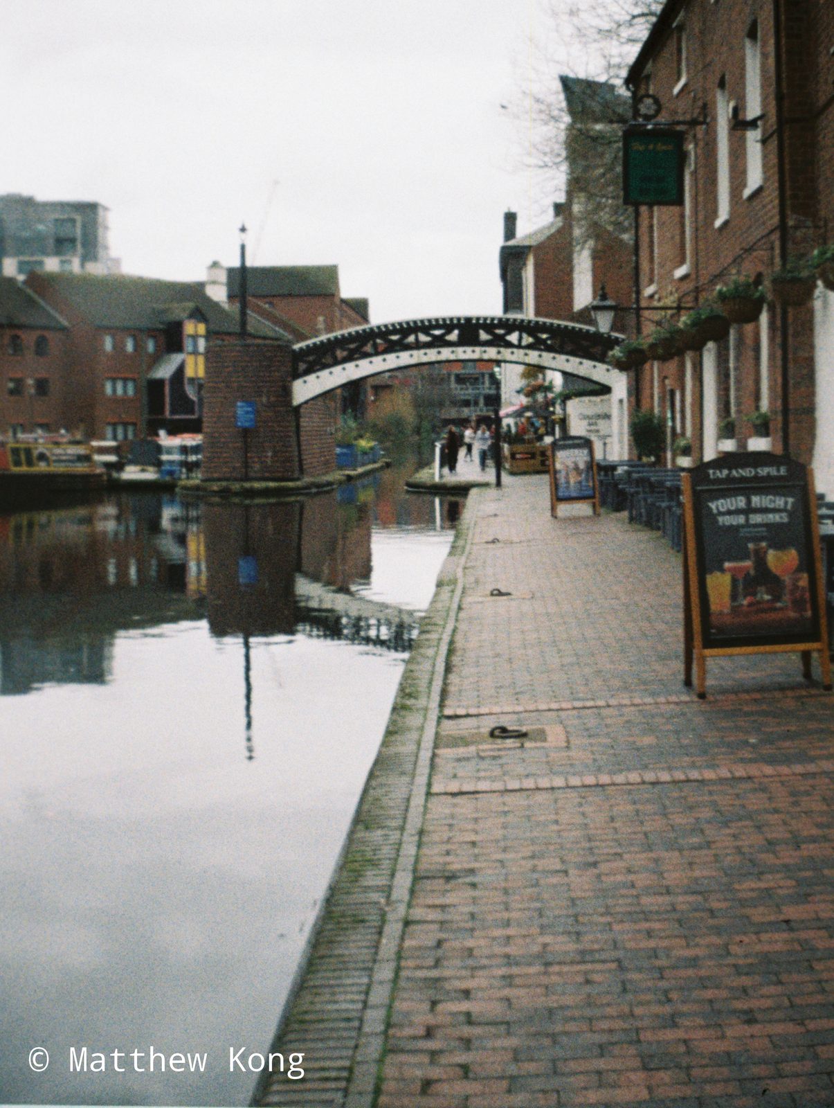 The towpath outside the Tap and Spile, with the cast-iron footbridge over the canal ahead.