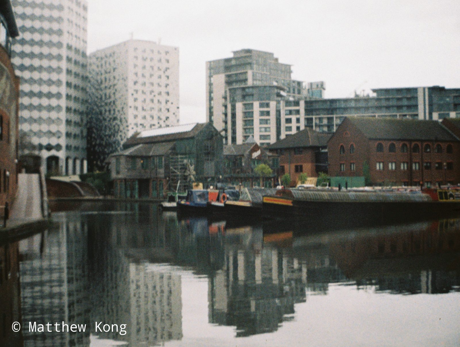 Gas Street Basin, narrowboats moored against the old wharf buildings with the city towers behind.